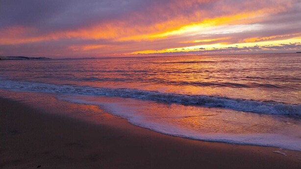 Een strand met golven en een zonsondergang.