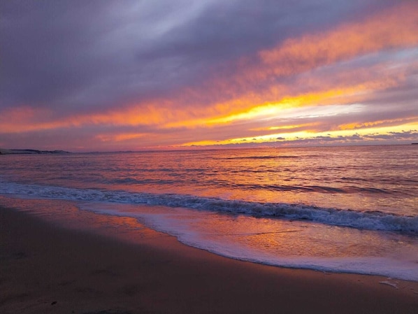 Ein Strand mit Wellen und einem Sonnenuntergang.