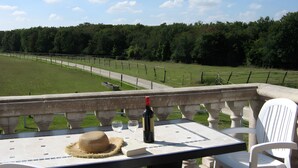 Een terras met een tafel, stoelen, een fles en een hoed.