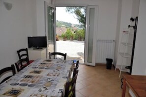 A dining area with a table covered in a tablecloth, chairs, a television, and a view of the outdoors. - Sun Apartment in Villa Daria 2 km from the sea of the Gulf of Tigullio (Chiavari)