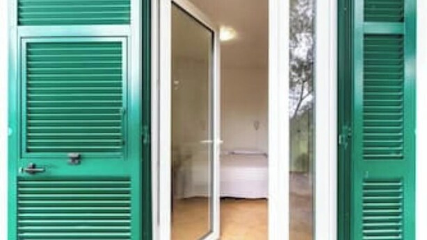 Una habitación con puerta corrediza de vidrio, una cama y pared blanca.