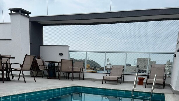 A rooftop pool with clear blue water, surrounded by lounge chairs and a modern architectural design. - Villa Bellagio (Ubatuba)