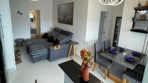 A modern living room with a sofa, a dining table with chairs, and a decorative vase. - Villa Bellagio (Ubatuba)