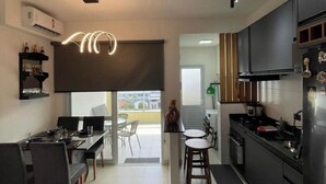 A modern kitchen with a dining area, a large window, and a staircase leading to an upper level. - Villa Bellagio (Ubatuba)