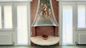 A room with a fireplace, a mural, and a round table with a bowl. - B002 - Bellaria, large apartment close to the sea (Bellaria)