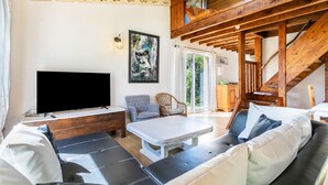 Ein Wohnzimmer mit einer Couch, einem Couchtisch, einem Fernseher und einer Treppe.