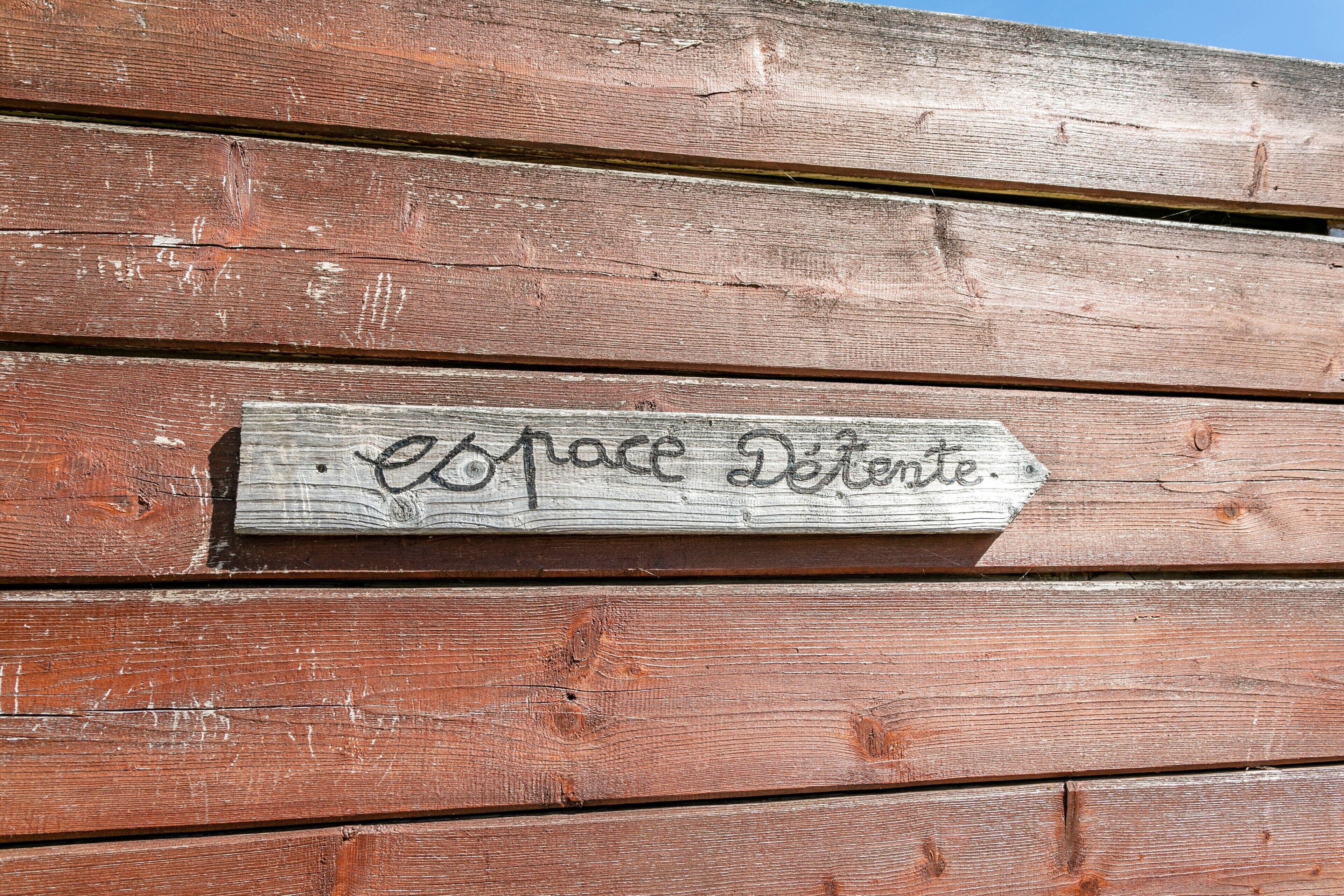 A wooden sign with the text 'espace detente' on a weathered wooden wall.