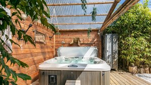 Ein Whirlpool auf einer überdachten Holzterrasse.