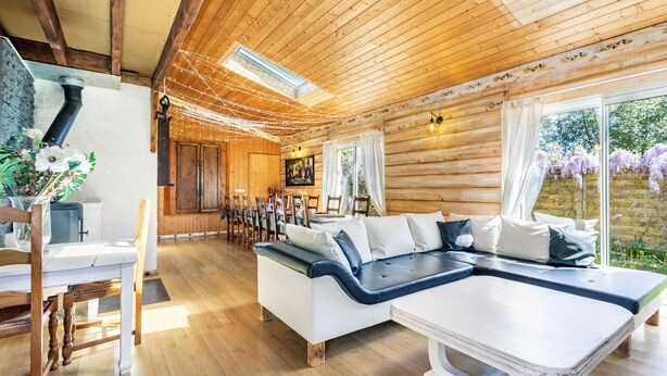Ein Holzblockhaus mit einer Couch, einem Esstisch und Stühlen.