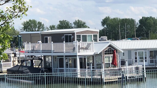 A waterfront house with a balcony, a covered deck, and a view of the water.