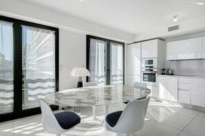 A modern kitchen with white cabinets, a built-in oven, and a microwave. - Juan les Pins Seafront – 2-Bedroom Bay Side Apartment (Antibes)