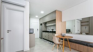 A modern kitchen with a dining area, a built-in bench, and a large mirror. - SC-401 | Tech Hub | Gym #SG08 (Florianópolis)
