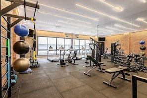A gym with exercise equipment, a brick wall, and a window. - SC-401 | Tech Hub | Gym #SG08 (Florianópolis)