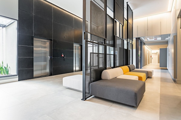 A modern lobby with a seating area, elevators, and a glass wall.