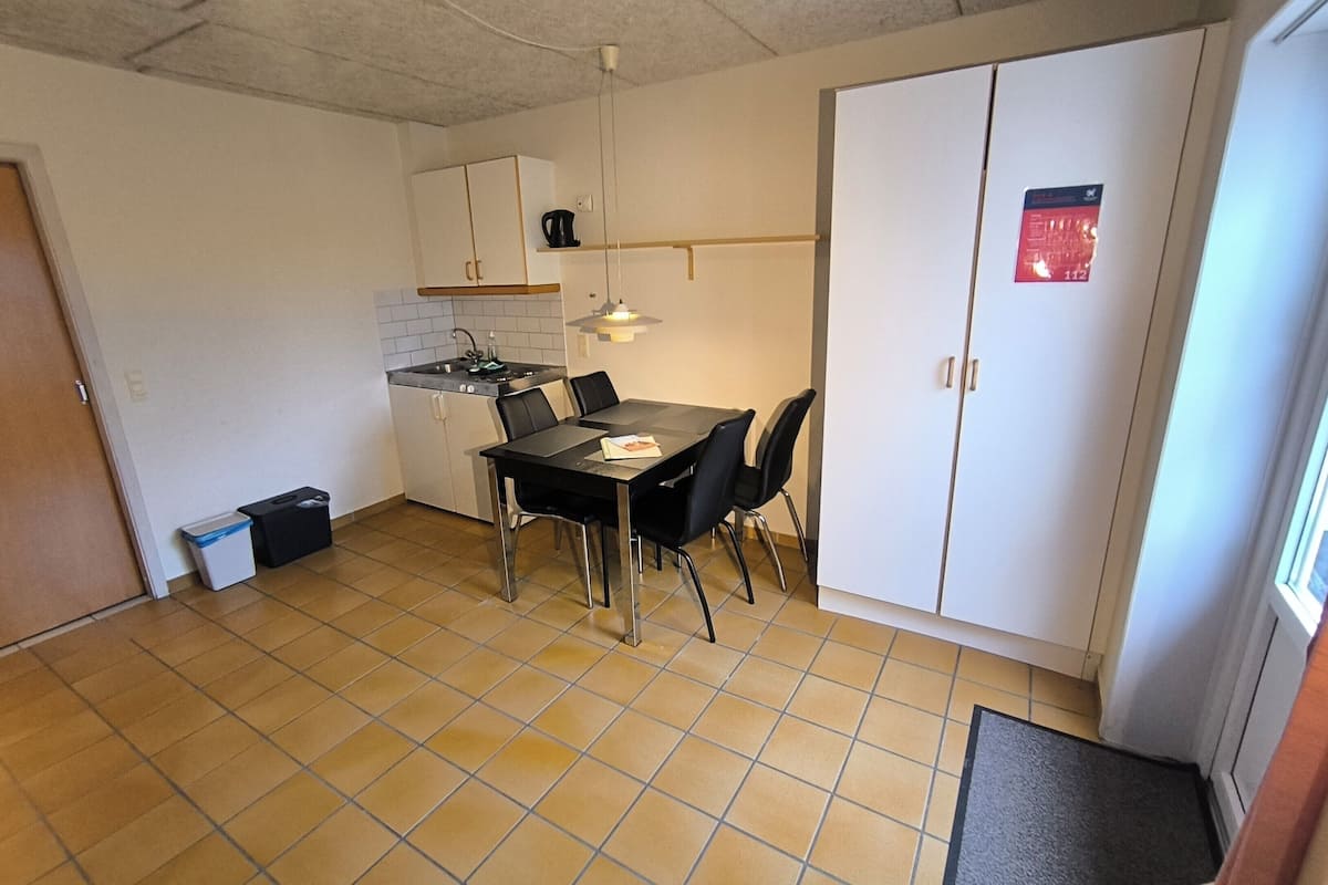 A compact kitchen with a dining table, chairs, and a small countertop.
