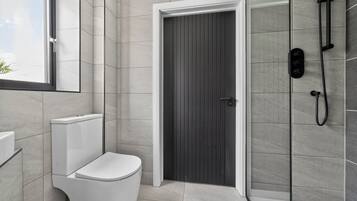 Un baño moderno con inodoro, cabina de ducha y puerta.