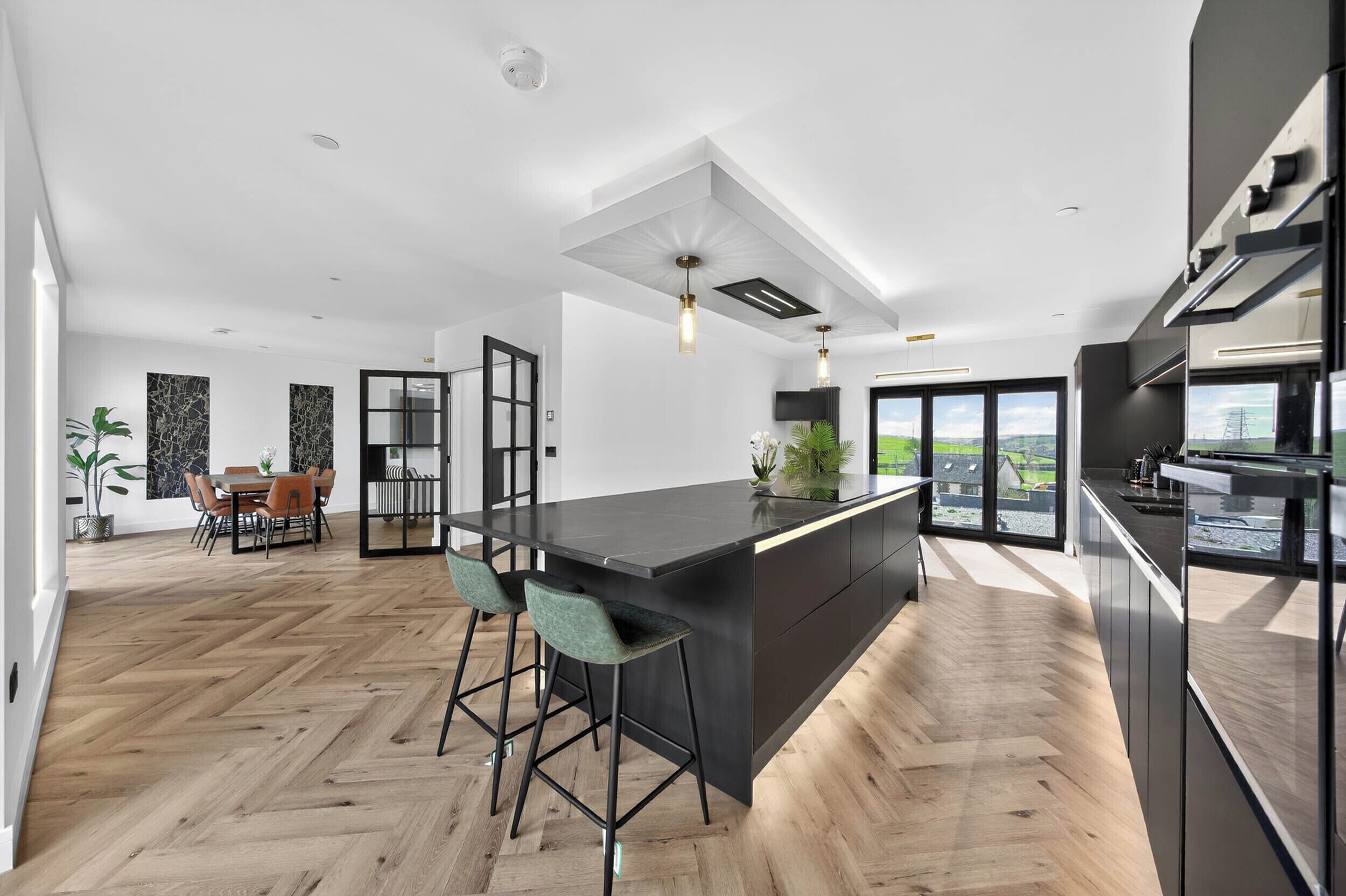 Una cocina moderna con una isla central, taburetes de bar y un comedor con vistas.