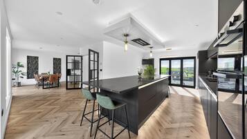 Una cocina moderna con una isla central, taburetes de bar y un comedor con vistas.