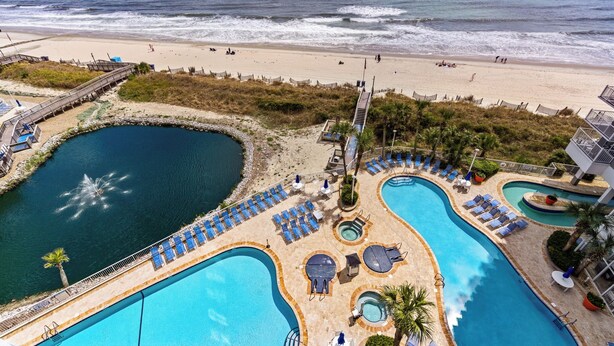 Un resort con varias piscinas, una playa y un paseo marítimo.