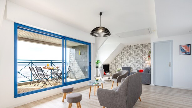 Un salon moderne doté d’une grande fenêtre, d’un coin repas et d’un escalier menant à un niveau supérieur.