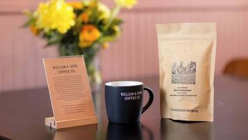 Une tasse à café et un sac en papier orné d’un logo, posés sur une table.