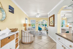 A spacious living area with a staircase, a dining area, and a view of the outdoors. - Barefoot Beach Resort E206 - Liquid Obsession (Indian Shores)