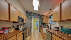 Eine Küche mit Holzausstattung, einer Mikrowelle, einem Kühlschrank, einem Toaster und einem Fenster.