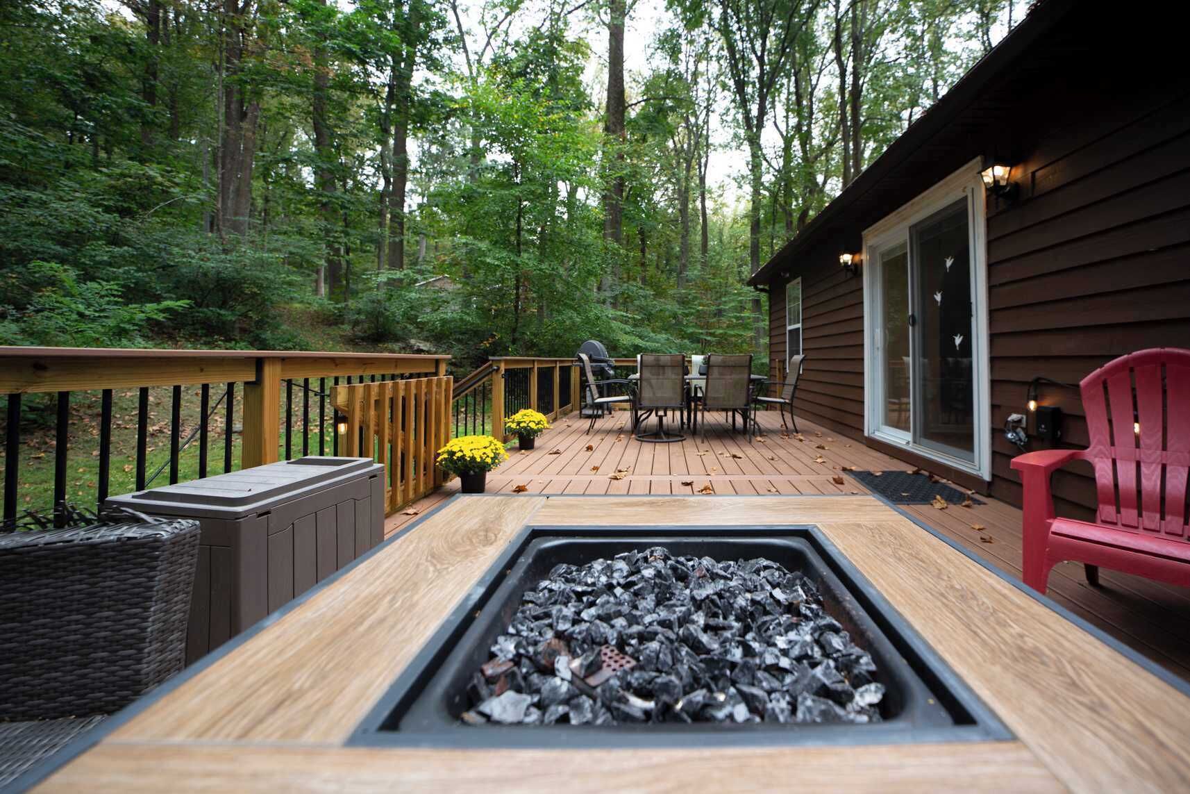 A deck with a fire pit, outdoor furniture, and a view of the forest.
