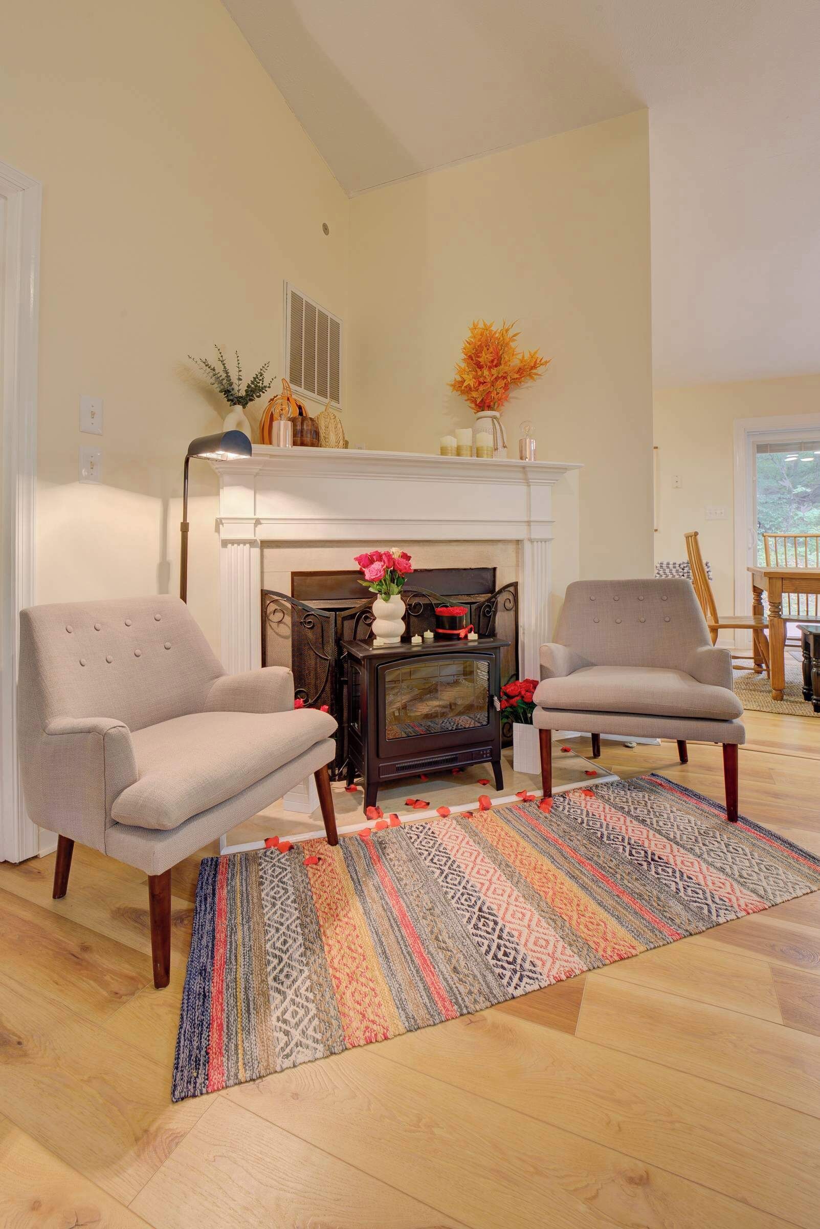 A living room with two armchairs, a fireplace, a patterned rug, and a wooden floor.