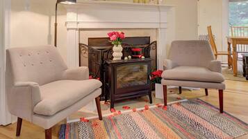 A living room with two armchairs, a fireplace, a patterned rug, and a wooden floor.