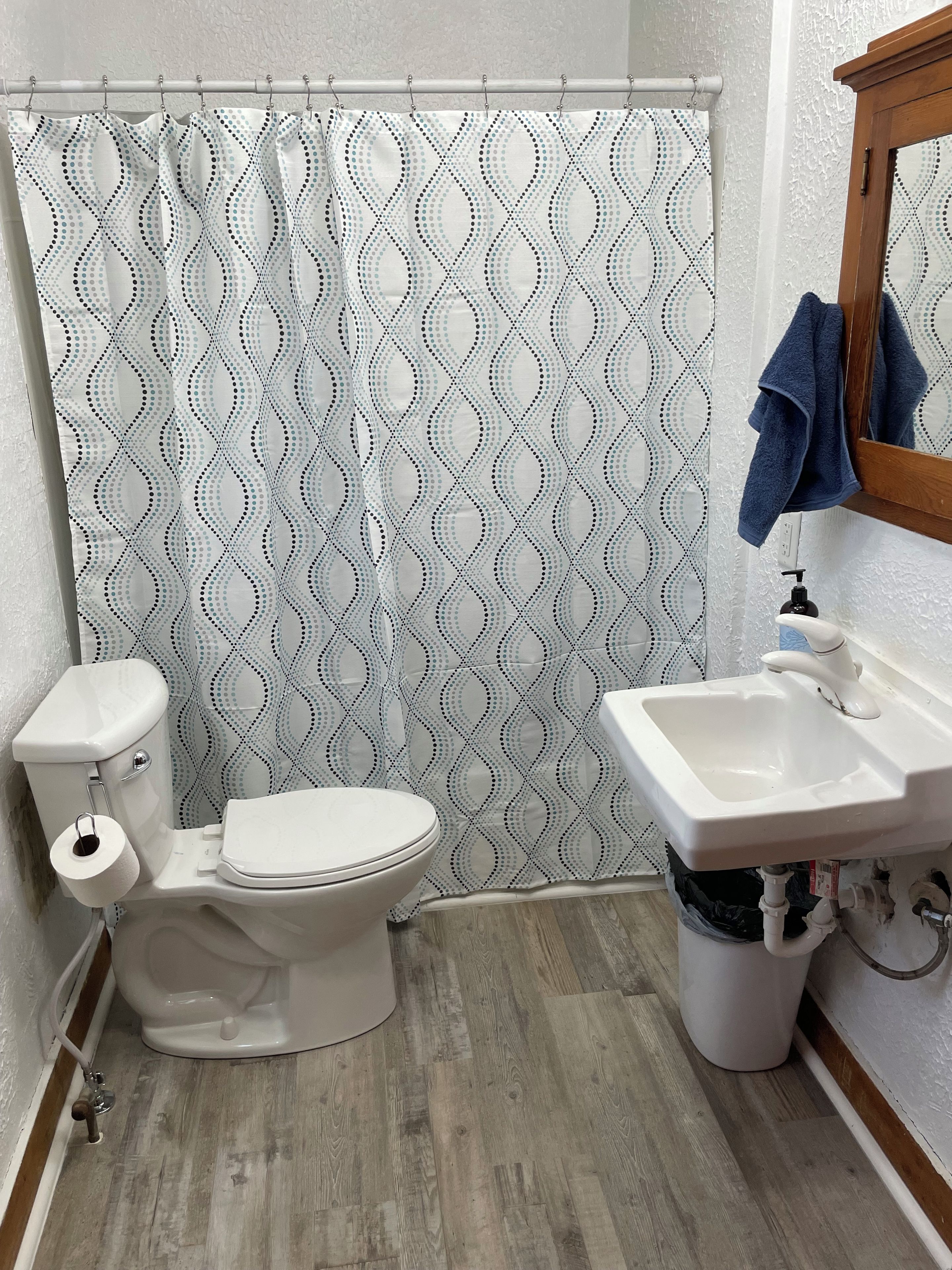 Un baño con inodoro, lavamanos y cortina de ducha.