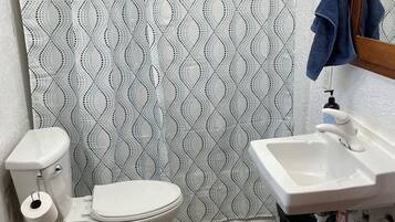 Un baño con inodoro, lavamanos y cortina de ducha.