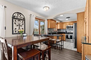 A modern kitchen with wooden cabinets, a large island, and a dining area with chairs.
