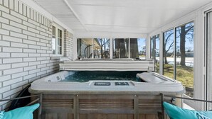 A hot tub with a wooden exterior, a window, and a view of trees and a road. - Lakefront Ranch | Hot Tub · 30-Day Min Stay (Waterford Township)