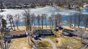 A residential area with houses, a frozen lake, and a clear sky. - Lakefront Ranch | Hot Tub · 30-Day Min Stay (Waterford Township)