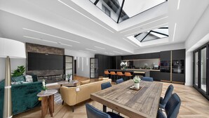 A modern interior with a dining area, kitchen, and seating space. - Ty Hir (Llanelli)