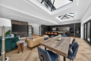 A modern interior with a dining area, kitchen, and seating space. - Ty Hir (Llanelli)