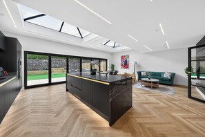 A modern kitchen with a central island, large windows, and a view of the outdoors. - Ty Hir (Llanelli)