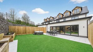 A modern house with a large backyard, a hot tub, and a dining area. - Ty Hir (Llanelli)