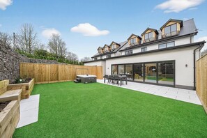 A modern house with a large backyard, a hot tub, and a dining area. - Ty Hir (Llanelli)