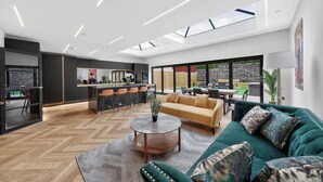 A modern living room with a sofa, coffee table, and a dining area with chairs. - Ty Hir (Llanelli)