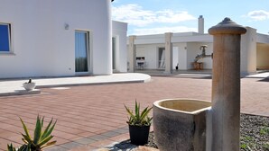 Ein modernes Gebäude mit Innenhof, Pflanzgefäßen und einem Wasserspiel.