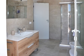 Un bagno moderno con box doccia in vetro, lavandino bianco e mobili in legno.