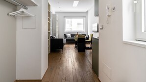 Ein Flur, der in einen Wohnbereich mit einer Couch, einem Tisch und einem Stuhl führt.