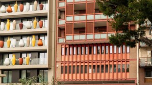 Ein mehrstöckiges Gebäude mit einer markanten Fassade, das große Vasen im Erdgeschoss und ein Musterwerk in den oberen Etagen zeigt.