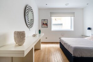 A bedroom with a bed, a desk, a mirror, a window, and a painting on the wall. - Leone Central Suite Bari by BarbarHouse (Bari)