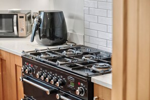 A kitchen with a gas stove, a coffee maker, and a microwave. - Central Belfast Apartments Rosetta Residence (Belfast)