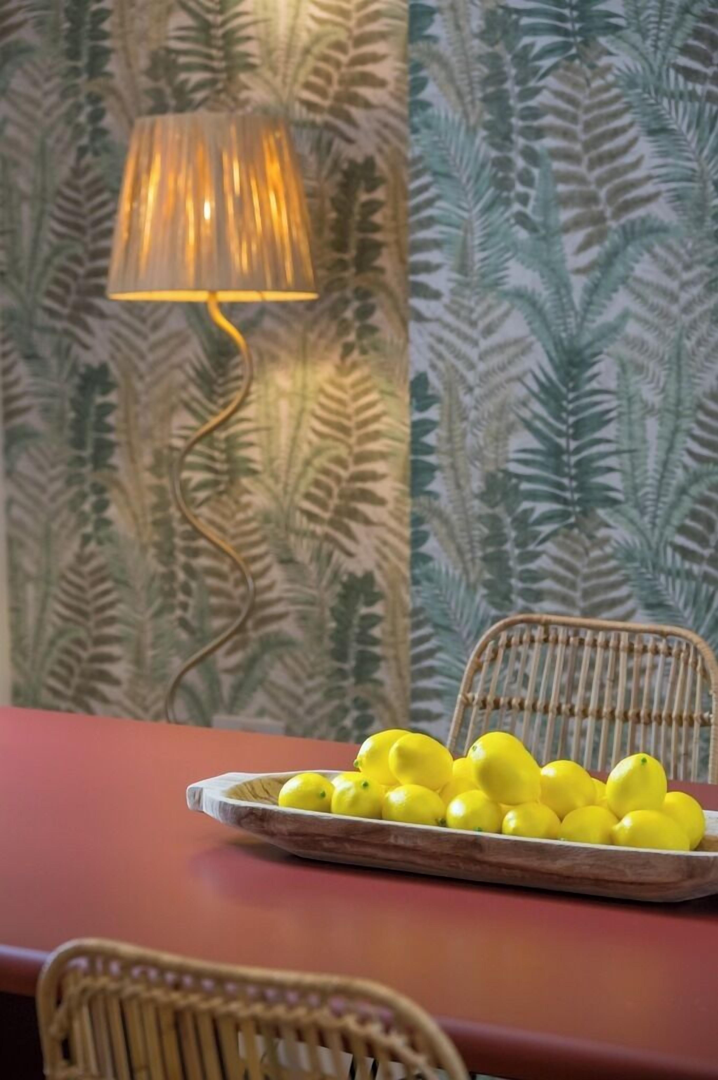 A dining area with a table, chairs, a lamp, and a fruit bowl.