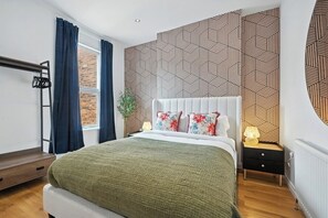 A modern bedroom with a large bed, a nightstand, a wall-mounted shelf, and a window with curtains. - Central Belfast Apartments Queens Residence (Belfast)