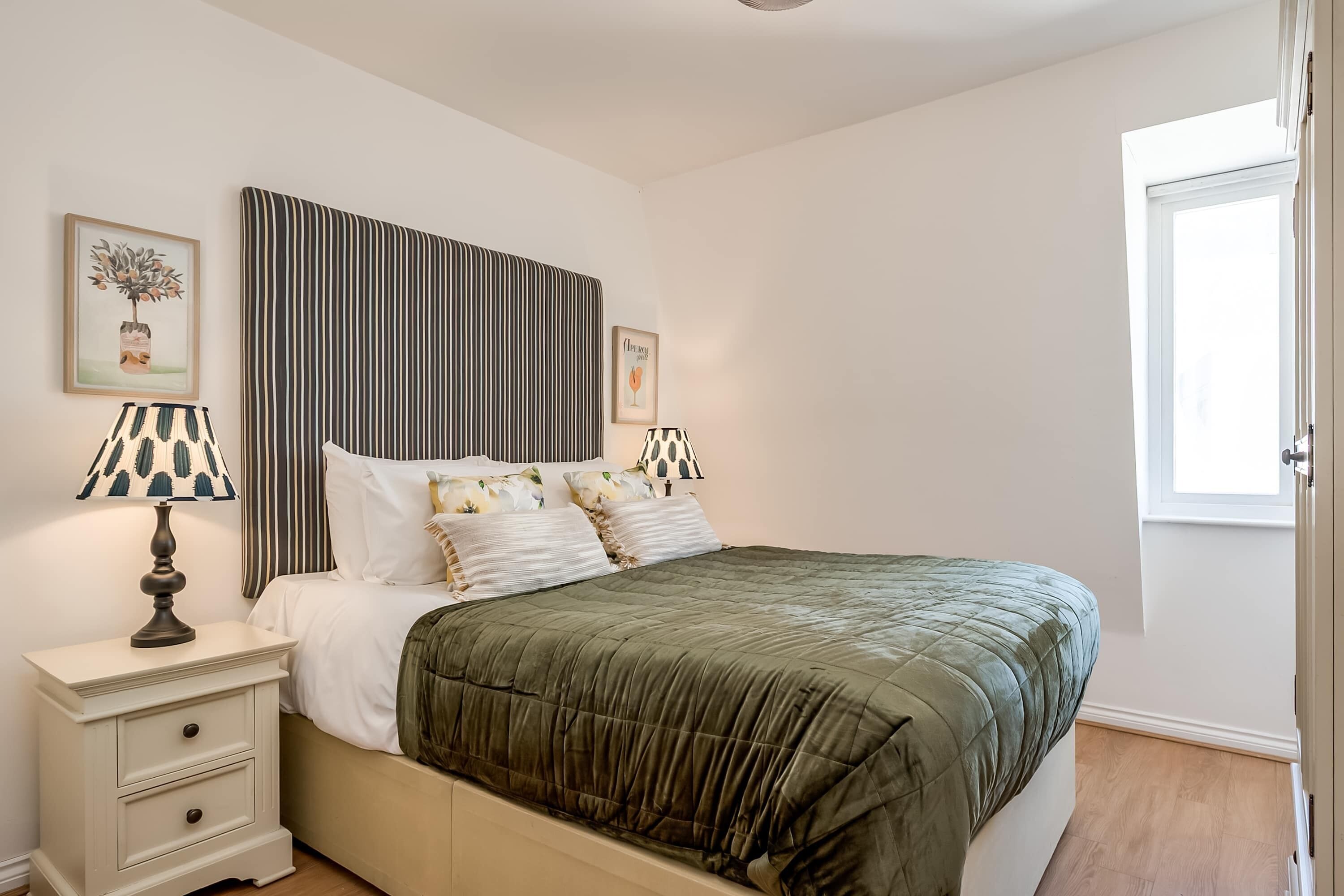 A neatly arranged bedroom with a bed, bedside tables, and a window.